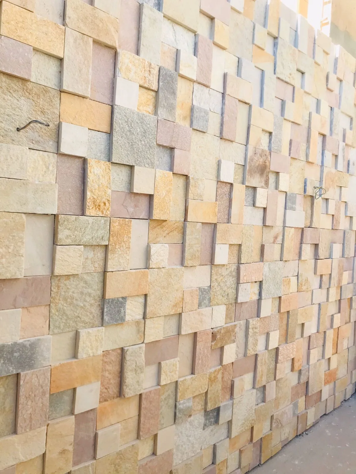 Detalhe próximo de mosaico em tons amarelos e neutros, com diferentes profundidades.