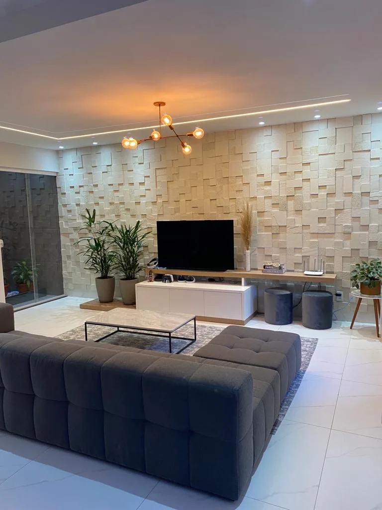 Sala com parede de mosaico claro, sofá e mobiliário diante do revestimento.