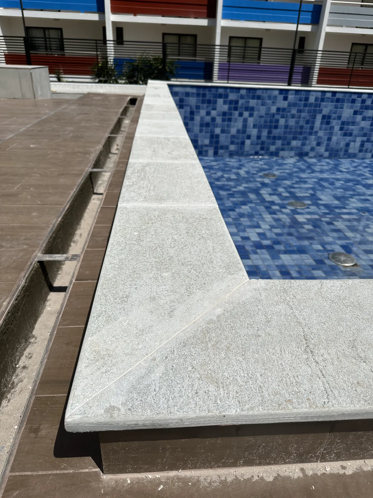 Detalhe próximo da borda de uma piscina vazia, com peças claras e encontro entre cantos.